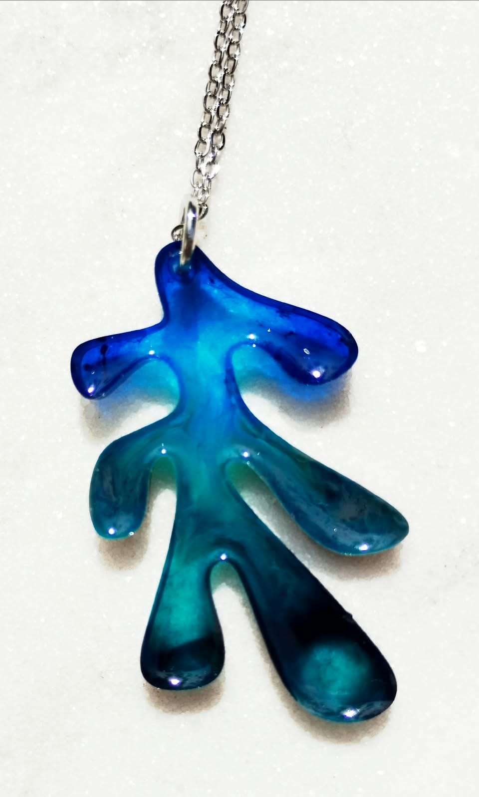 Pendentif pieuvre bleu turquoise avec chaîne argentée sur fond blanc