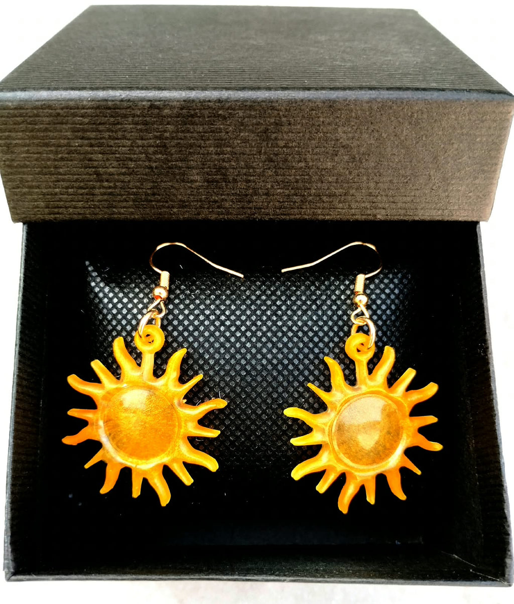 Boucle d'oreille en forme de soleil doré dans un écrin noir