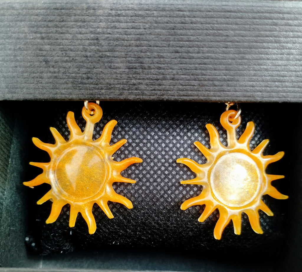 Gros plan sur les boucles d'oreille soleil dorées