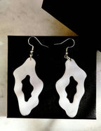 Boucles d’oreilles blanches organiques ajourées sur fond noir