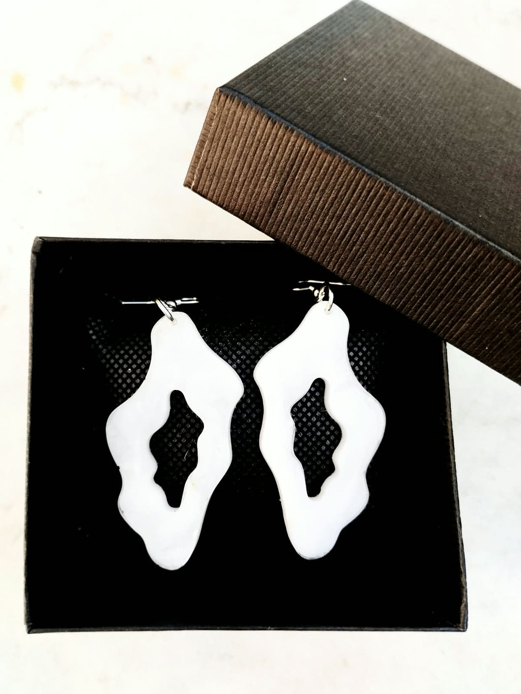 Boucles d’oreilles blanches organiques présentées dans une boîte