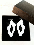 Boucles d’oreilles blanches organiques présentées dans une boîte