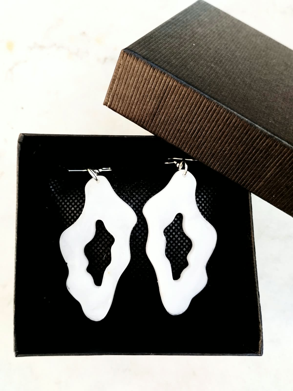 Boucles d’oreilles blanches organiques présentées dans une boîte